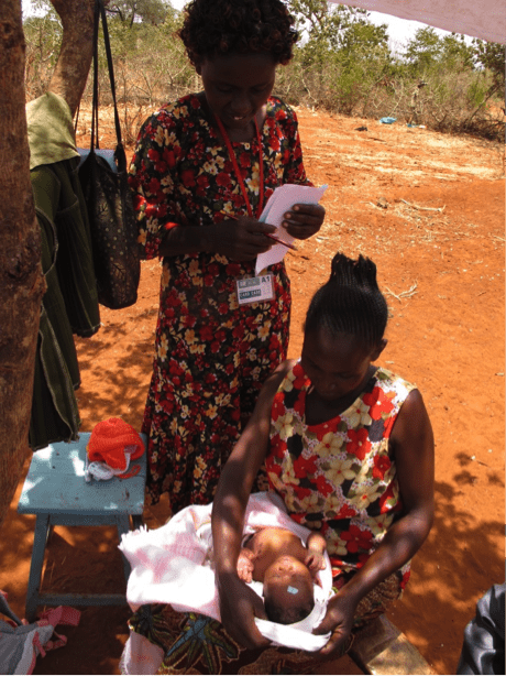 Women caring for baby under tree shade