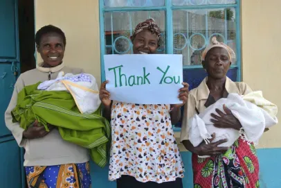 Women holding babies and thank you sign